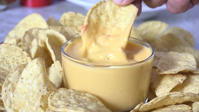 Dipping a corn tortilla chip into cheese sauce
