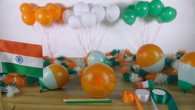 Tilt shot of beautiful festival decoratives for Republic Day celebrations in India. Decorated wooden table with 'Happy Republic Day' festive card  tricolor ribbons  balloons  and Indian national fl...