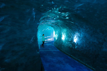 Female traveler walks along a path running through a breathtaking glacier.