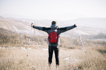 Back view of man with spread out hands holding poles