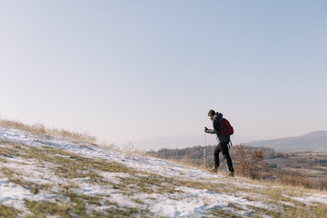 Side view of hiker walking on hill during winter