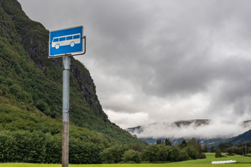 Bus stop sign, green Norway countryside mountains 