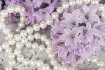 Romantic gift jewelry background with delicate flowers for wedding, festive, beauty design. Spring flowers hyacinths and pearls on white vintage background close up. 