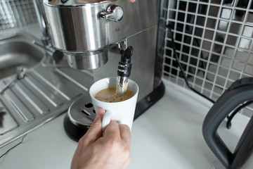 Guy prepare delicious aromatic coffee in a coffee machine. A simple way to make coffee