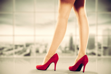 Woman legs with red heels and office interior 