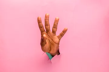 Fotobehang black person hand through a hole in a cardboard indicating number four © Confidence
