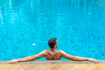 The guy is relaxing by the pool on a hot summer day
