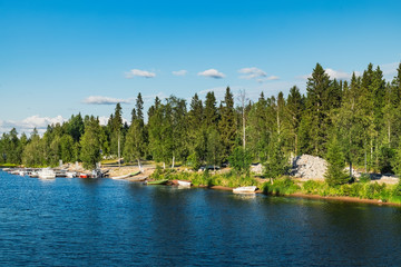 Panoramic summer view of Iijoki river near Municipality of Ii in the region of Northern Ostrobothnia, Finland. The old wooden pier and boat on the shore