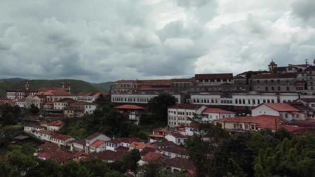 Motion time lapse following clouds passing above the colonial mining city Ouro Preto in Minas Gerais, Brazil, lighting up parts of the city through clearances panning across the historic town centre