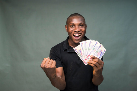 young black man holding some cash, feeling excited and celebrates