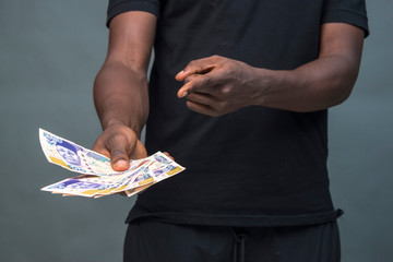 young african man holding some cash and pointing at it