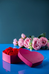 Heart shaped open gift box on blue background.