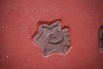 stone aztec symbol on red wall