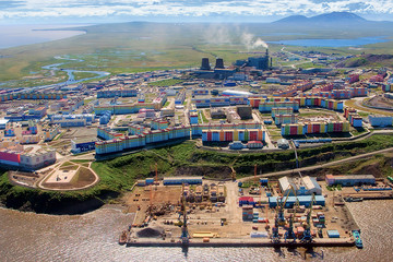 Fototapeta premium Top view of the city of Anadyr. Anadyr is the administrative center of the Chukotka Autonomous Region of Russia. Beautiful aerial view of the seaport, colorful buildings and the summer Arctic tundra.