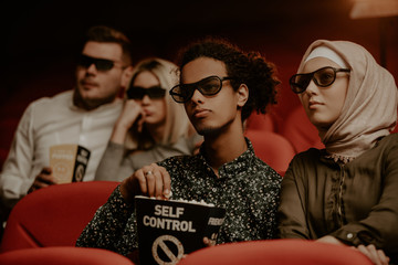 Obraz premium Multiethnic friends with popcorn watching movie in cinema