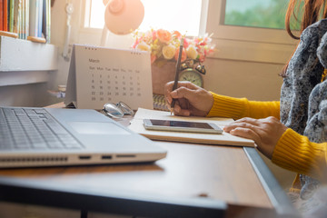 Calendar reminder event concept. Woman hand planner or organizer writing on diary book and 2021 Calendar page. Student planning appointment, noted and count Down schedule day