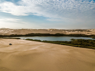 Aerial view of car in the desert and lake of peru