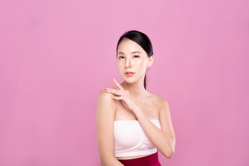 Fototapeta na wymiar Beautiful Young Asian woman with clean fresh white skin touching her own face softly in beauty pose. Girl touching with fingers in pink background. Facial treatment, cosmetology, spa, make up concept.