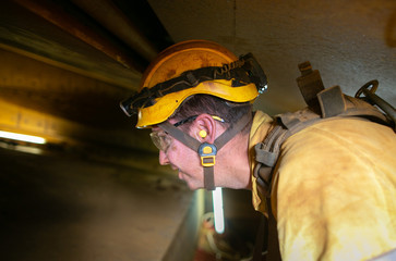 Closeup construction worker wearing safety helmet, clear glass ears noise protection headlamp while...