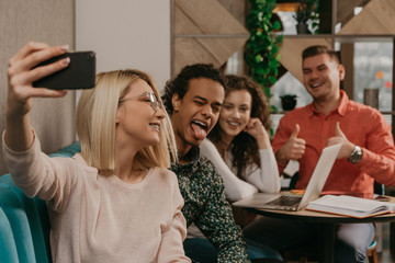 Diverse group of smiling young designer working together over a laptop during a meeting in the boardroom of a modern office