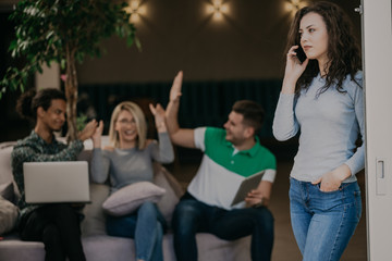 Woman talking on smartphone, in background team of young coworker team, mixrace people