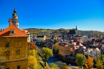 Obraz premium The view of the city of Cesky Krumlov in the late afternoon, clear blue sky, contrasting with the yellow of the leaves and the orange of the old city roof, Czech Republic