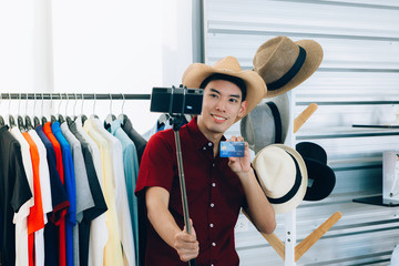 A Young Asian man are broadcasting live, selling online and showing that payment can be made via credit card.