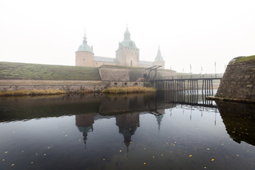 Bridge to Kalmar castle entrance an autumn day with heavy fog. © tomalv
