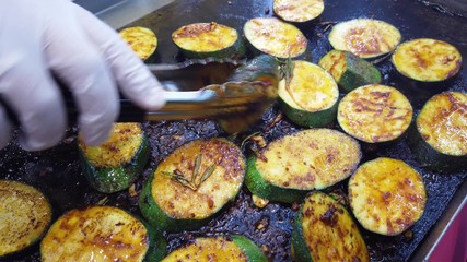 Roasting round slices of zucchini, vegetarian cuisine. The cook flips the fried slices to the other side.