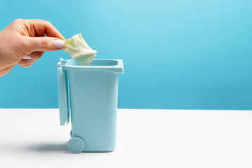 Female hand throws food garbage in trash can, side view