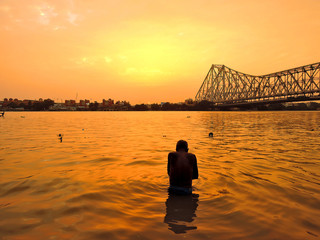 Silhouette of a man taking bath in ganges river during sunset