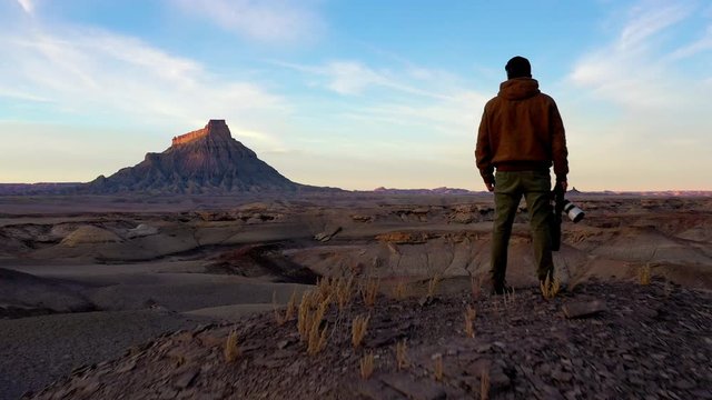 Photographer Stands Overlooking Otherworldly Alien Southwest Desert Landscape with Factory Butte in Distance