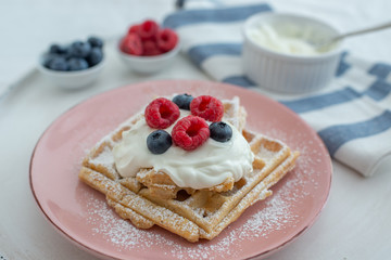 Fresh sugar waffles with castor sugar and berries