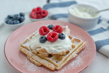 Fresh sugar waffles with castor sugar and berries