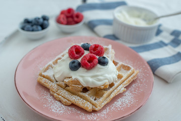 Fresh sugar waffles with castor sugar and berries