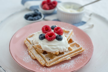 Fresh sugar waffles with castor sugar and berries