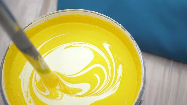 Yellow concentrated color paint is mixed with white paint. Wall painting concept. Slow motion and close-up view