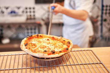 Baked tasty margherita pizza in Traditional wood oven in Neapolitan restaurant, Italy. Original neapolitan pizza. Red hot coal.