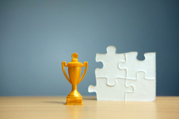 Golden trophy with white puzzle on a wooden table