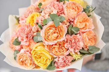 European floral shop. Beautiful bouquet of mixed flowers in womans hands. the work of the florist at a flower shop. Delivery fresh cut flower.