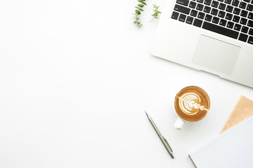 Top view of white office desk table with laptop computer, cup of coffee and supplies. Minimal...