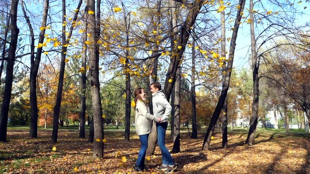 pregnant woman and her husband kiss under a tree in the fall autumn slow motion