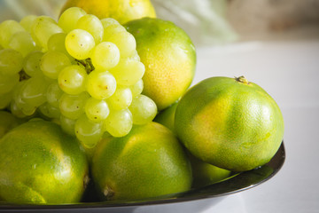 Green tangerines and grapes. Fancy fruits. Background
