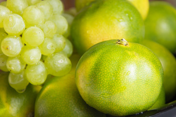 Green tangerines and grapes. Fancy fruits. Background