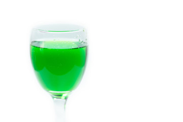 Pouring green water into a drinking glass on white background