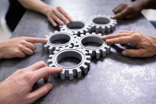 Businesspeople Joining Gears On Desk