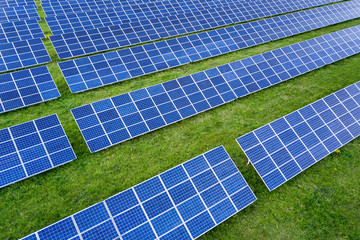Surface of solar photo voltaic panels system producing renewable clean energy on green grass...