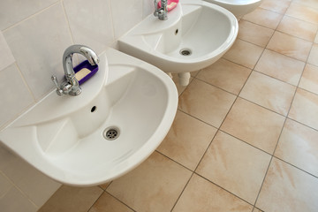 White ceramic washing basins with shiny stainless steel water tap.