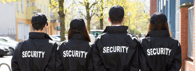 Rear View Of Security Guards Standing In A Row