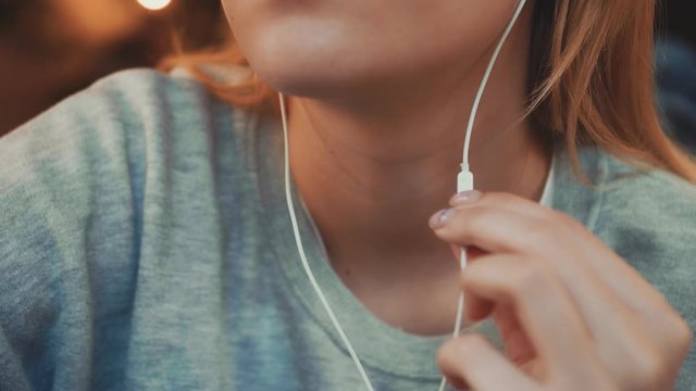 Young girl switches music in headphones at cafe